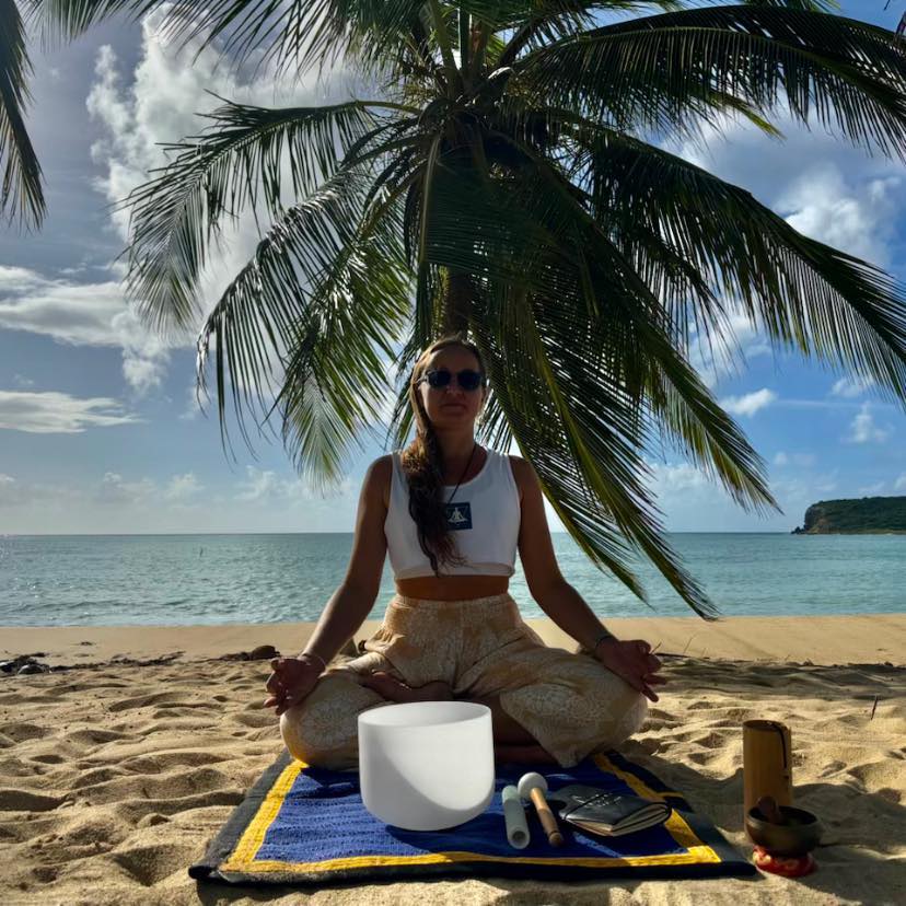 yoga teacher with sound bowl on the beach